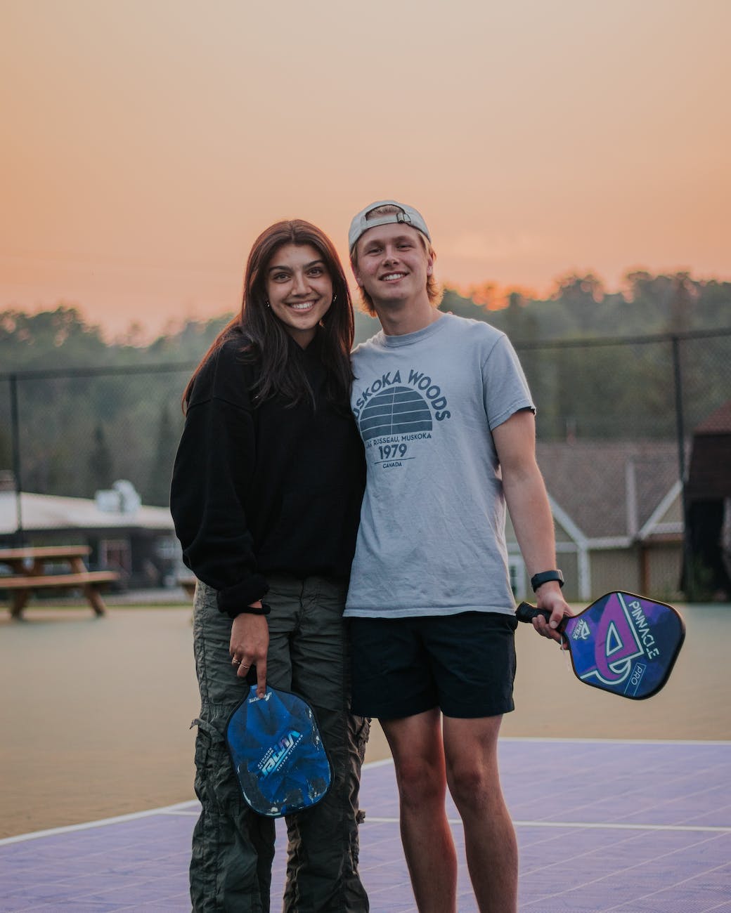 young man and woman standing on a pickleball court